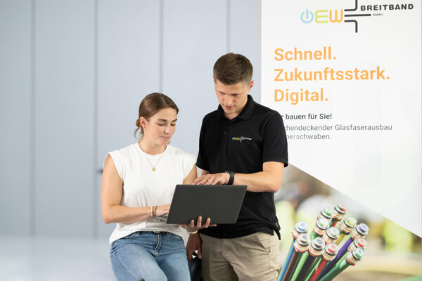Zwei Mitarbeiter unterhalten sich und arbeiten gemeinsam an einem Laptop.